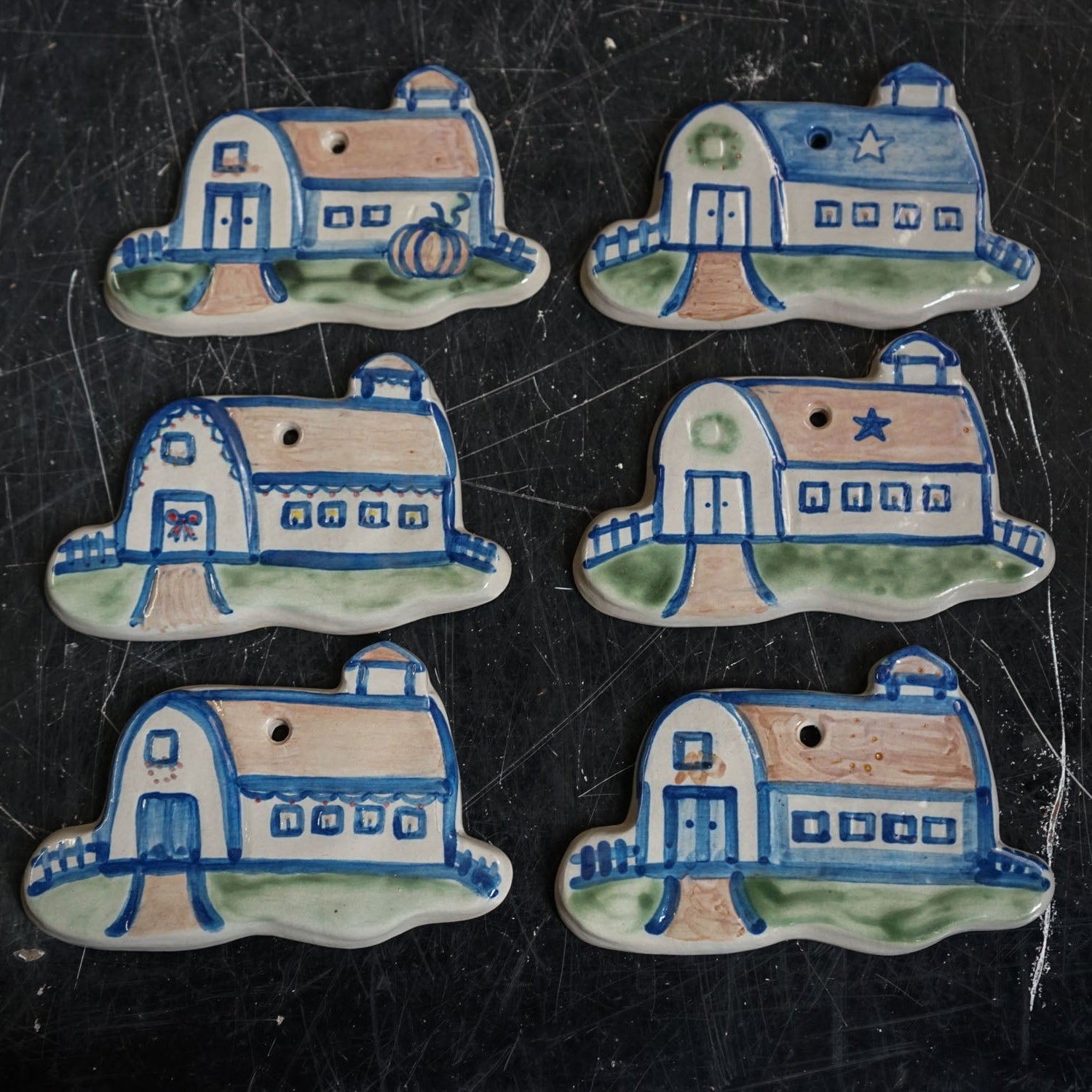 Set of six ceramic house-shaped tiles with blue and brown designs on a black surface.